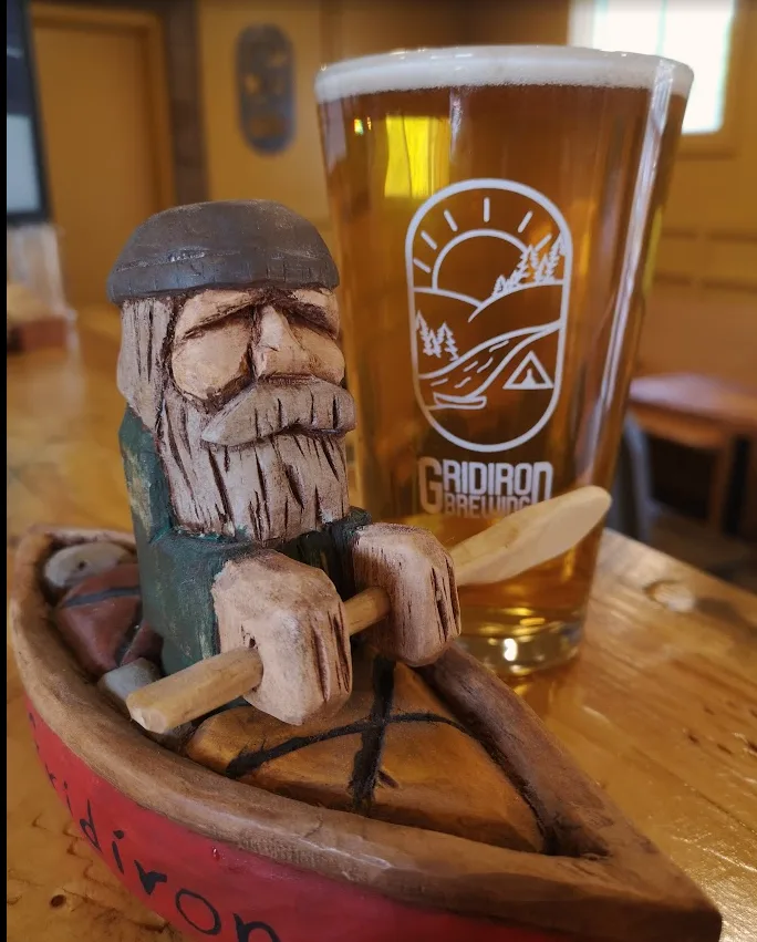 A carved wooden figure beside a fresh Gridiron pint